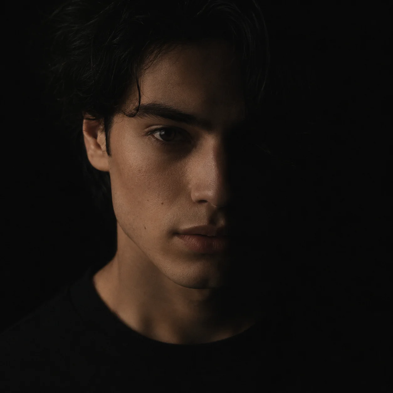 Moody black pfp close-up portrait with face partly in shadow, calm expression, for a mysterious low-key Discord avatar