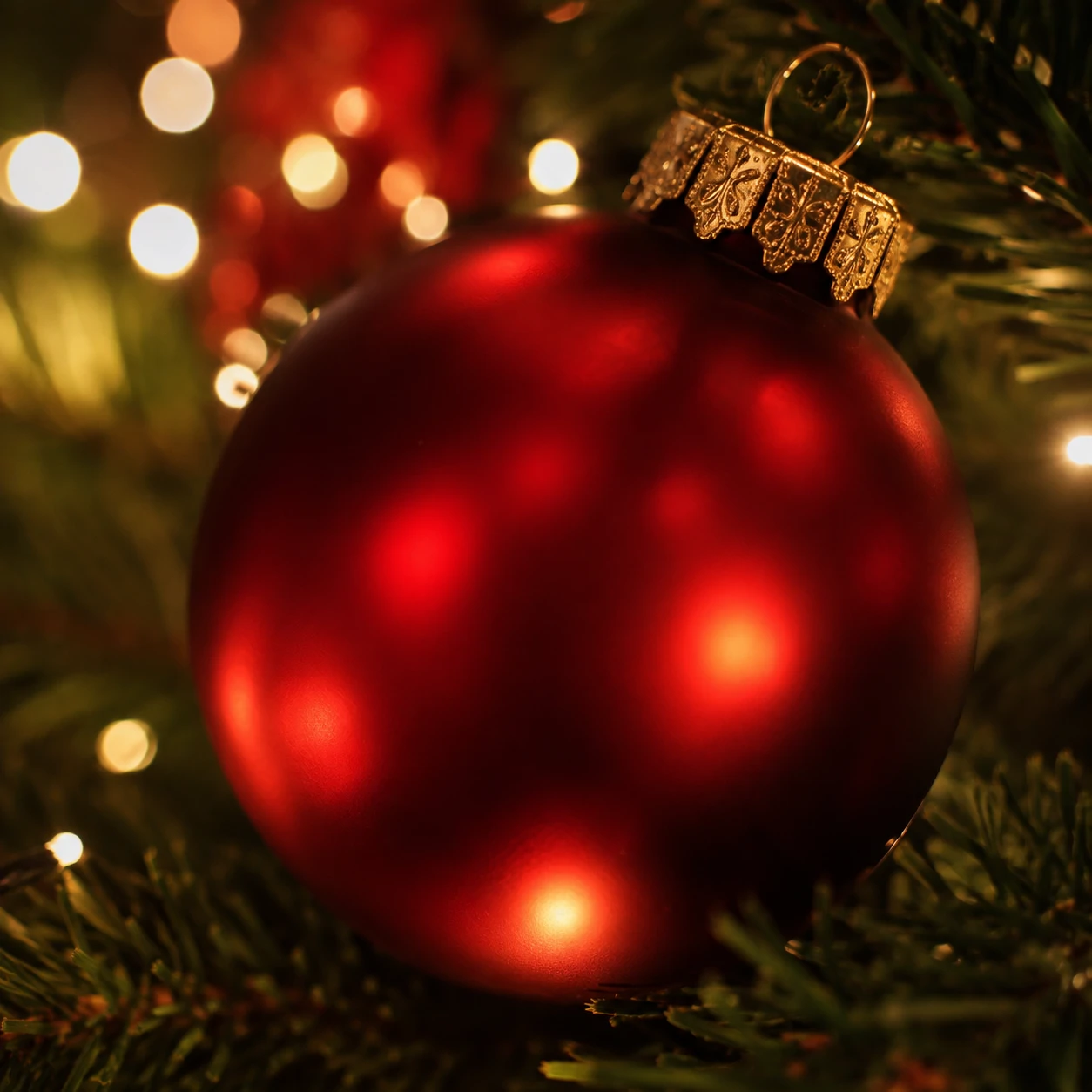 Aesthetic Christmas profile picture of a red glass ornament reflecting fairy lights up close