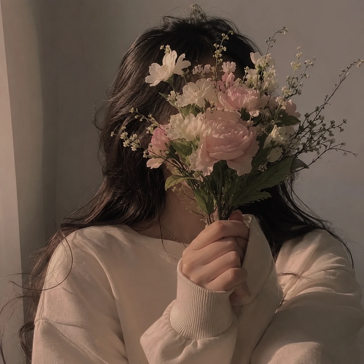 Girl covering her face with flowers for an unknown girl pfp.