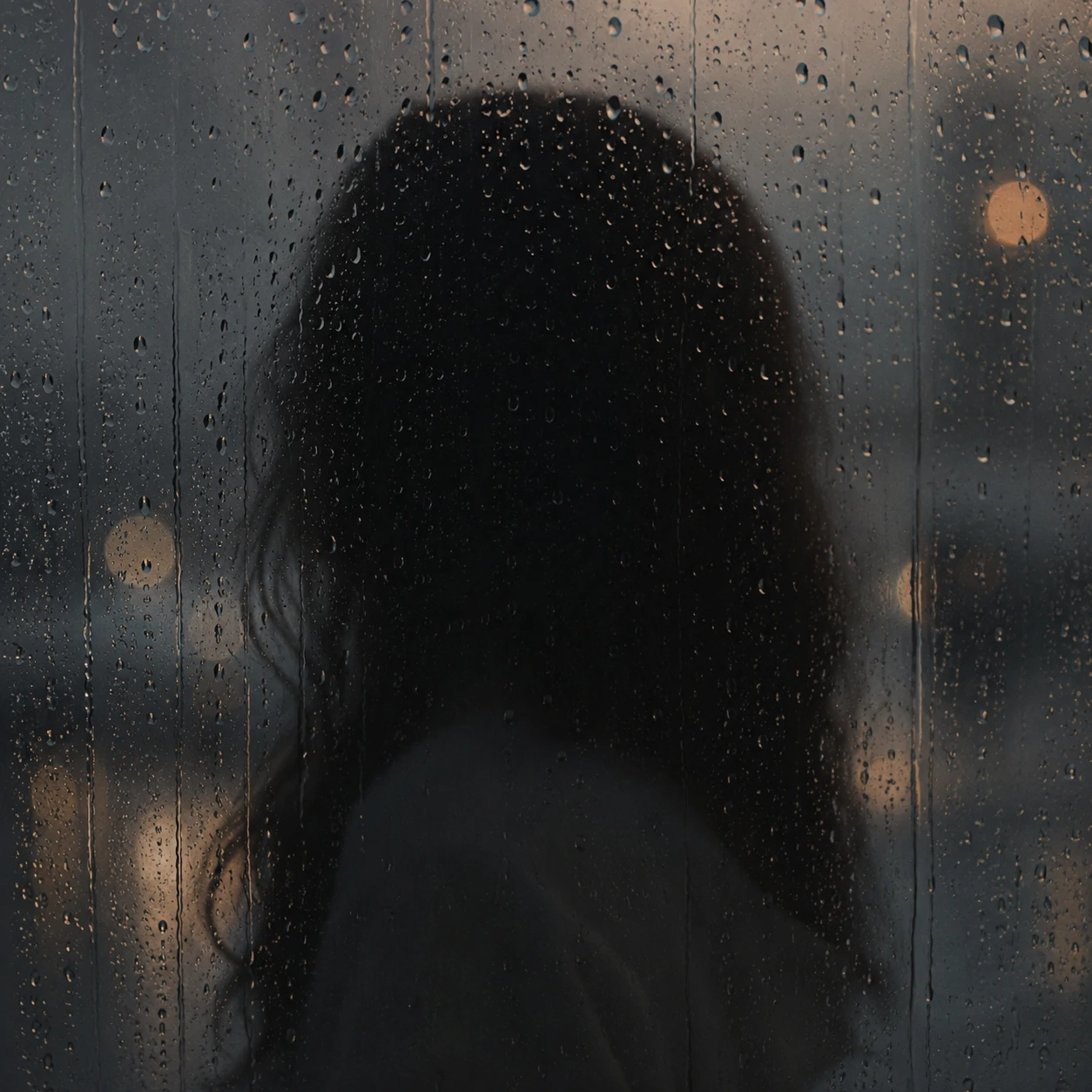 Person behind rainy glass used as a dreamy unknown pfp aesthetic.